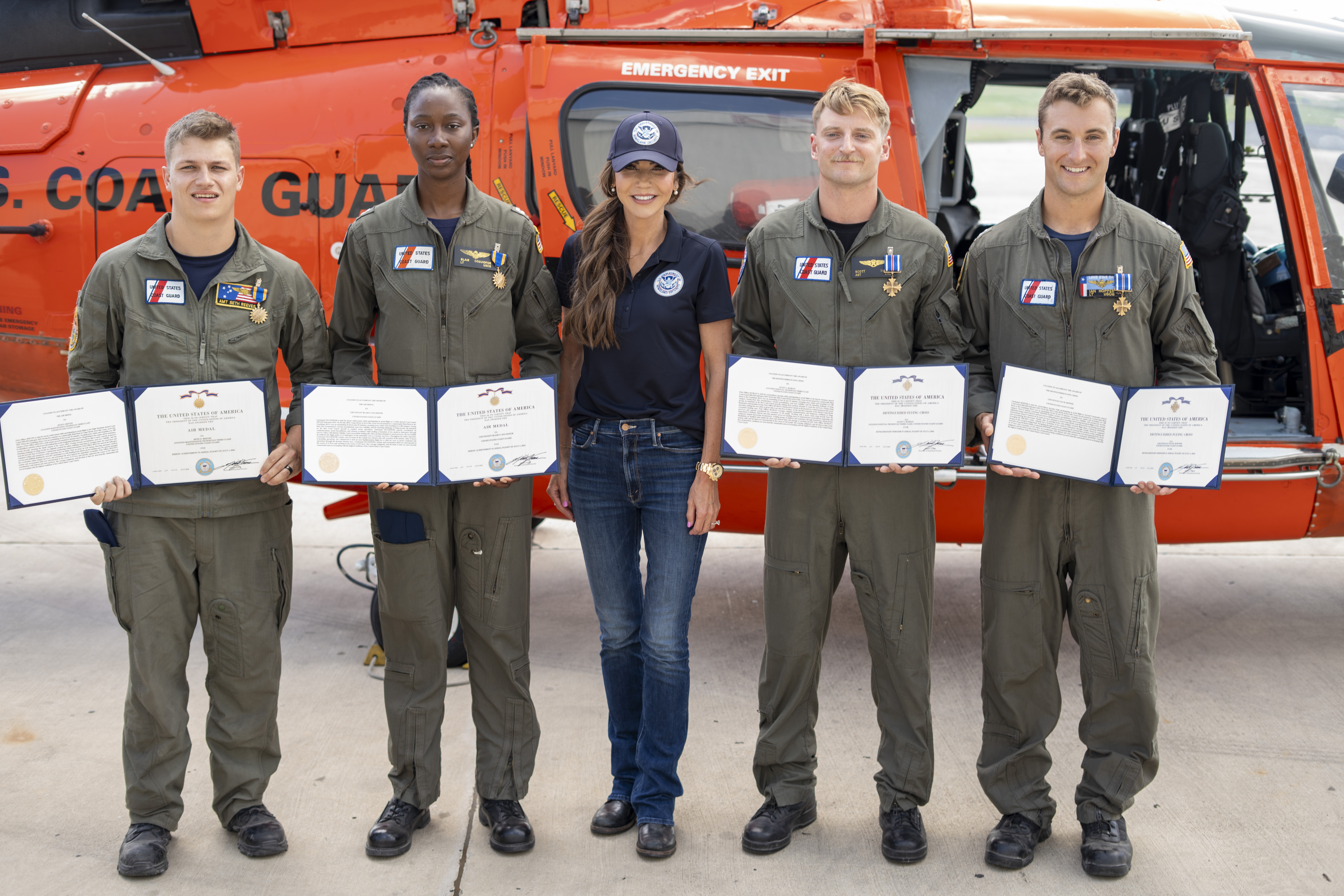 Secretary Kristi Noem presents medals to Lieutenant Ian Hopper, Lieutenant Blair Oguiofor, Petty Officer 3rd Class Scott Ruskan, and Petty Officer 3rd Class Seth Reece of Air Station Corpus Christi during a ceremony on July 11, 2025. The medals recognize their roles in the Camp Mystic rescue on July 4, when Coast Guard crews evacuated dozens of campers and staff amid flash flooding at the Guadalupe River. (U.S. Coast Guard photo by Petty Officer 3rd Class Perry Shirzad/Released) Secretary Kristi Noem presents medals to Lieutenant Ian Hopper, Lieutenant Blair Oguiofor, Petty Officer 3rd Class Scott Ruskan, and Petty Officer 3rd Class Seth Reece of Air Station Corpus Christi during a ceremony on July 11, 2025. The medals recognize their roles in the Camp Mystic rescue on July 4, when Coast Guard crews evacuated dozens of campers and staff amid flash flooding at the Guadalupe River. (U.S. Coast Guard photo by Petty Officer 3rd Class Perry Shirzad/Released)